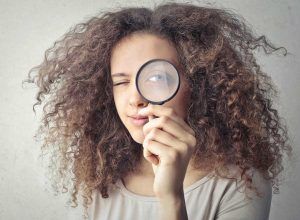 Rapariga com lupa na mão à frente do seu olho