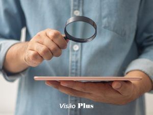 Utilizador de um tablet com uma lupa na mão para ver melhor